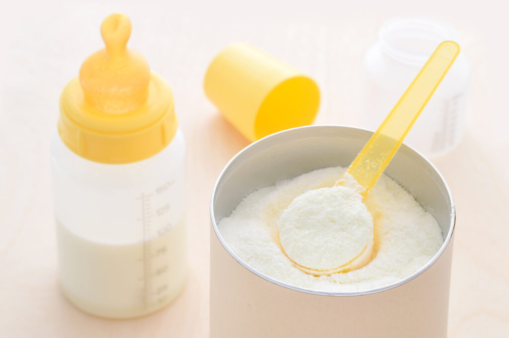 pote de fórmula infantil com mamadeira ao lado