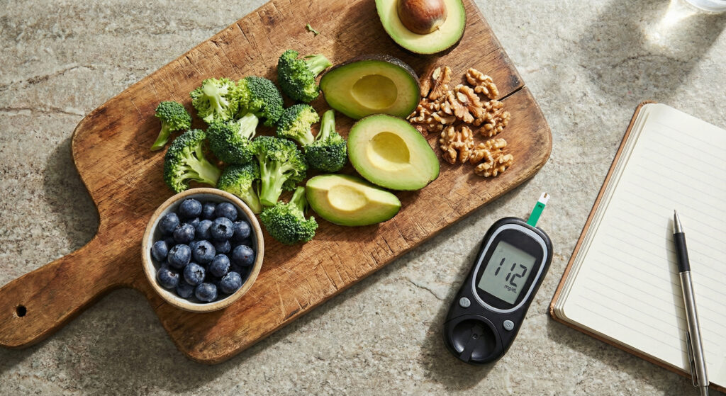 vegetais, frutas e grãos ao lado de caderno e aparelho de glicose