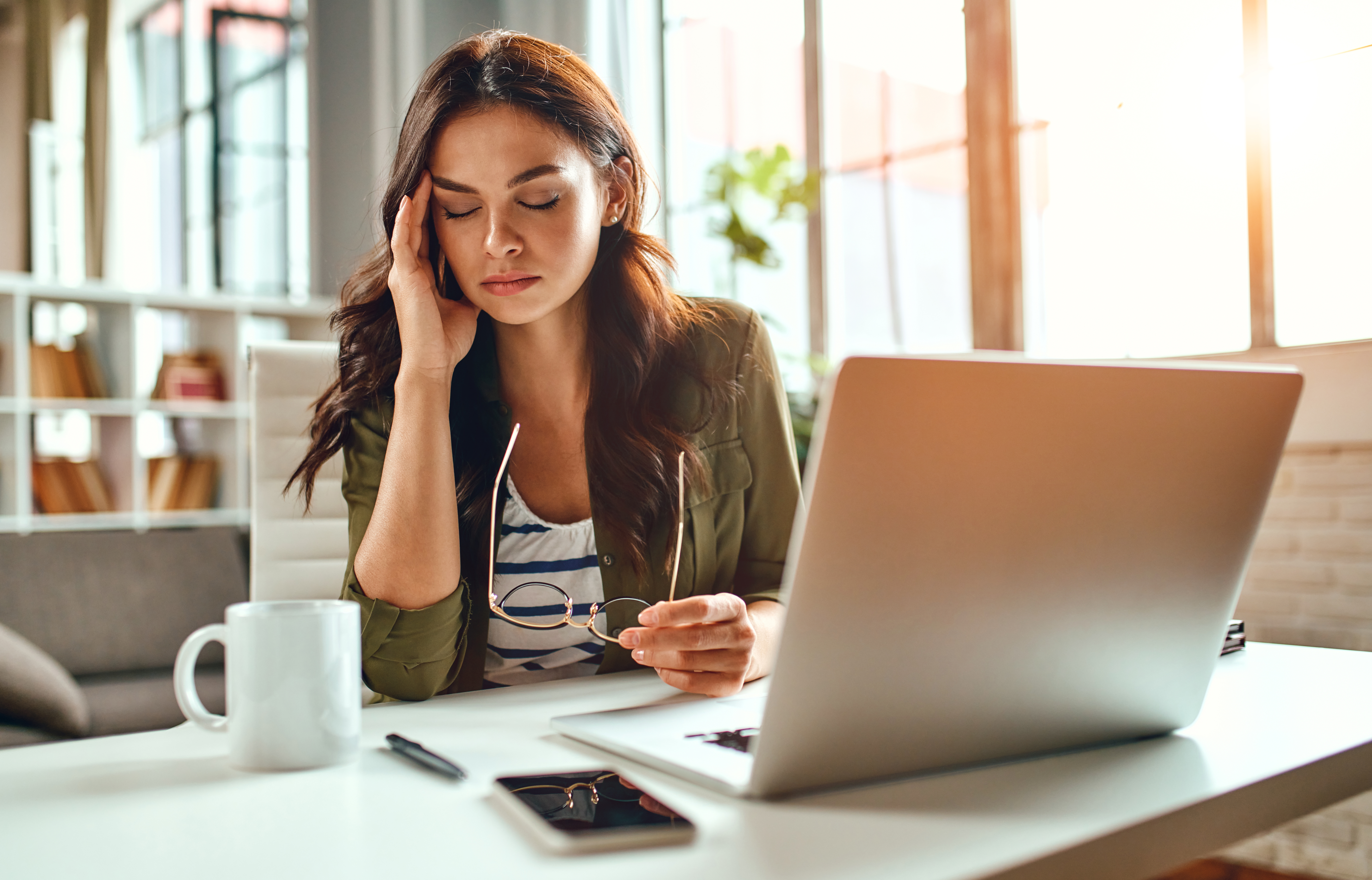 mulher com a mão na cabeça na frente do computador estressada