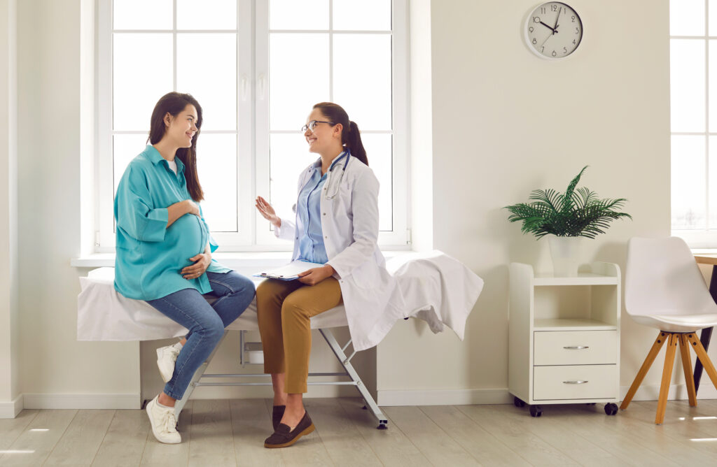 grávida sentada em maca consultando com médica pré-natal