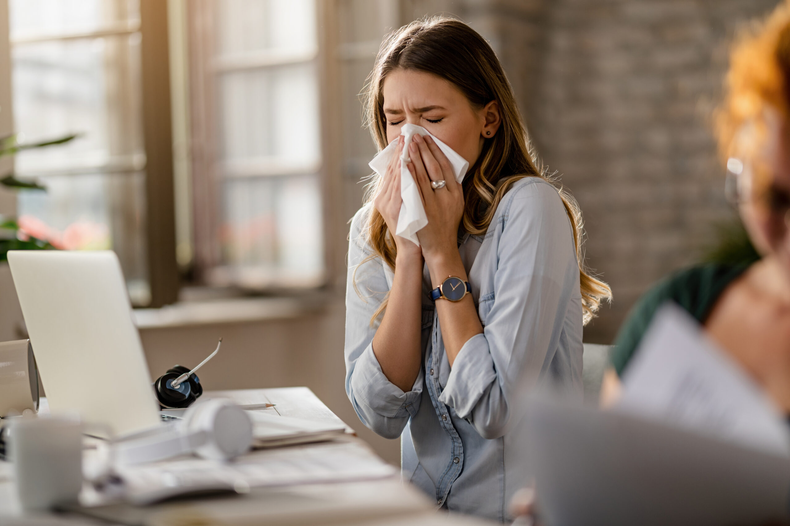 mulher espirrando, demonstrando sintomas de alergia
